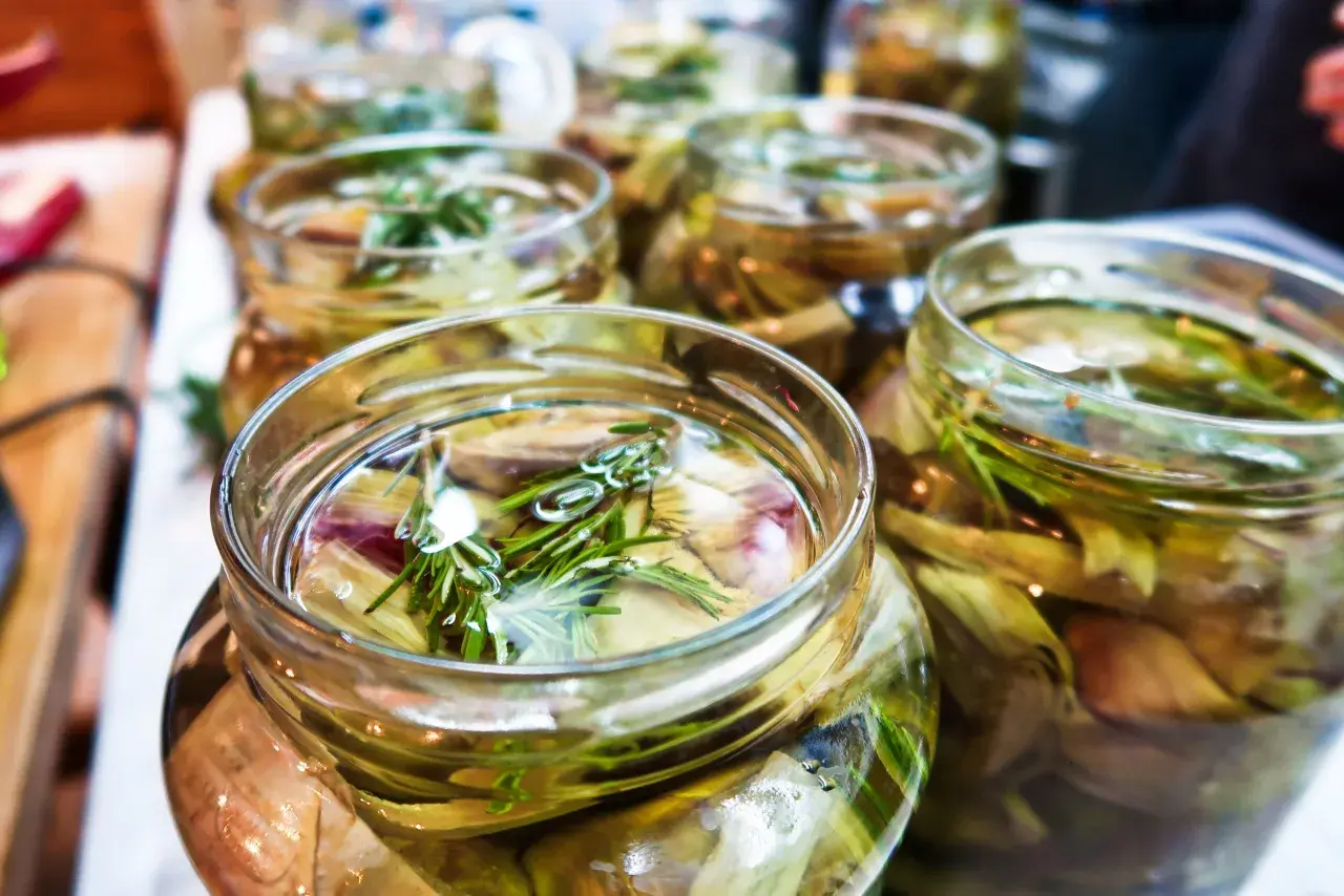 Jars filled with pickled artichoke hearts and rosemary sprigs, ready for a delicious meal.