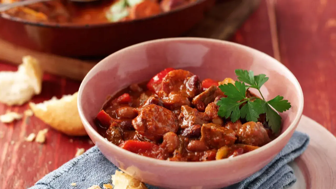 A hearty bowl of Spanish beef dishes, featuring tender beef chunks, beans, and peppers in a rich, savory sauce, garnished with fresh parsley.