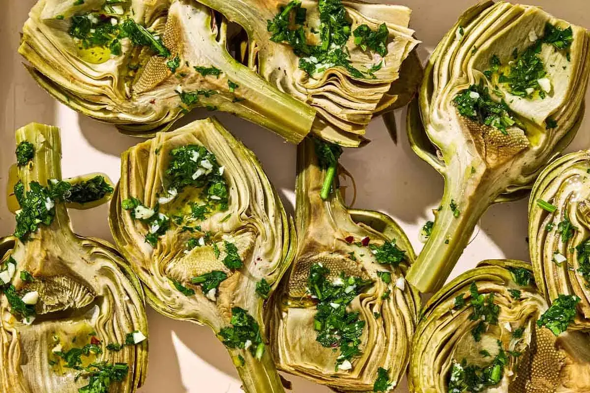 Halved artichokes, seasoned with herbs and garlic, ready for a delicious grilled artichoke recipe.