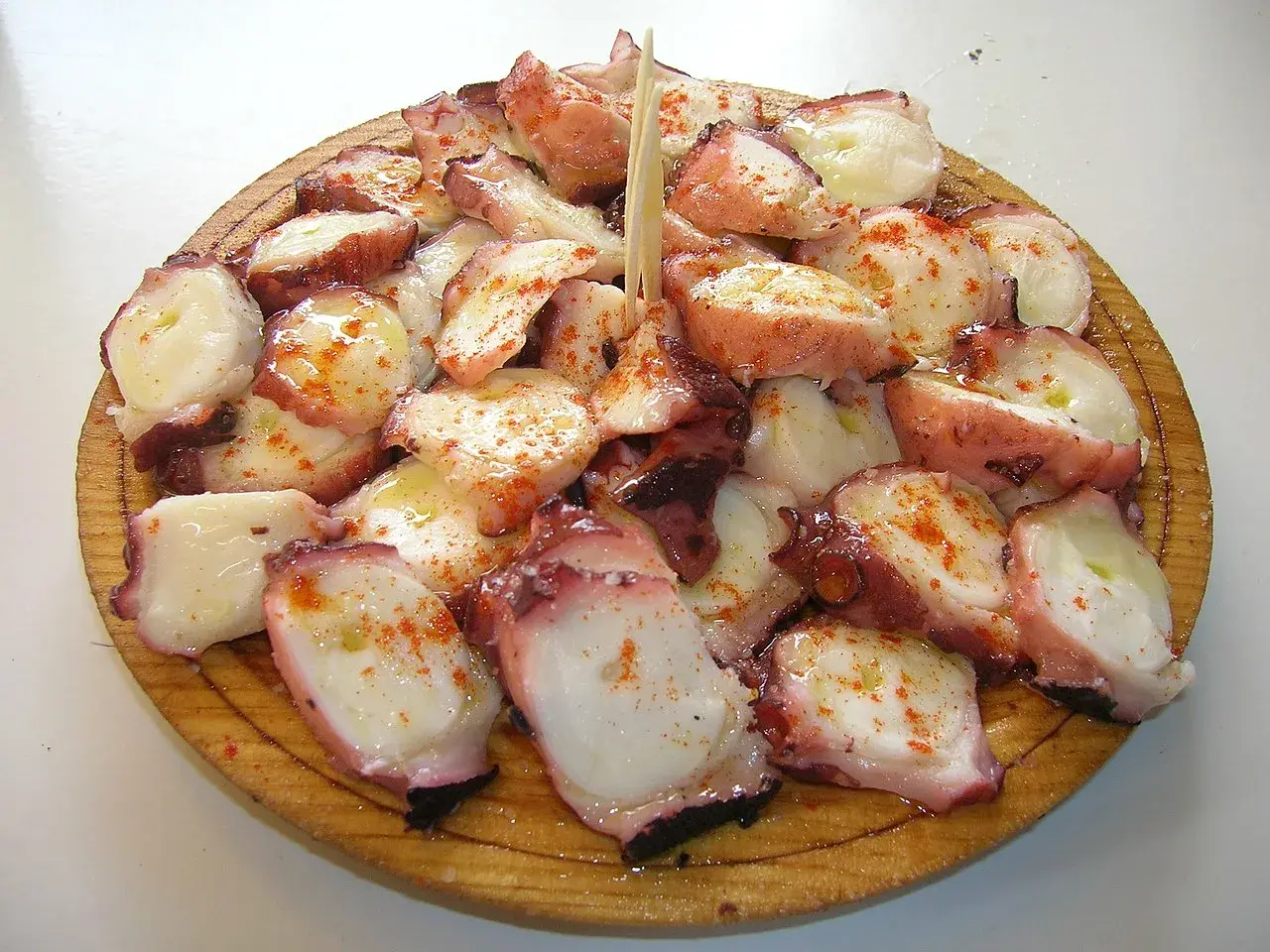 A delicious serving of pulpo a feira, tender octopus seasoned with paprika and olive oil, artfully arranged on a wooden platter.