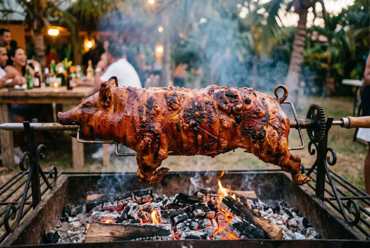 A whole spanish lechon, glistening and perfectly roasted, spins over glowing coals at an outdoor party.