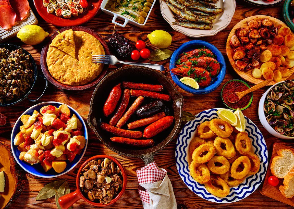 A vibrant spread of Spanish tapas: fried calamari, grilled sardines, chorizo, patatas bravas, and more. These small plates are perfect for sharing!