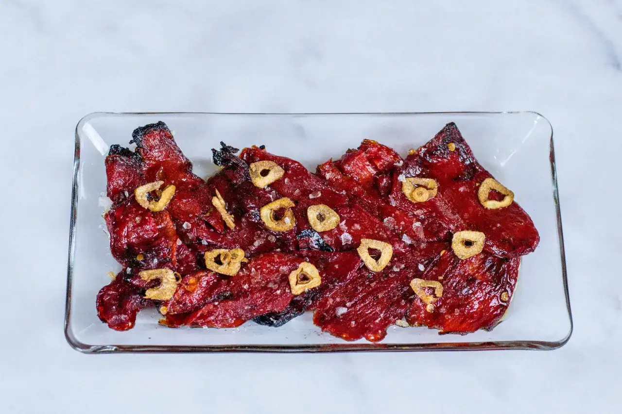 Thinly sliced steak tapas, glistening with a savory glaze and topped with crispy garlic slices and sea salt.
