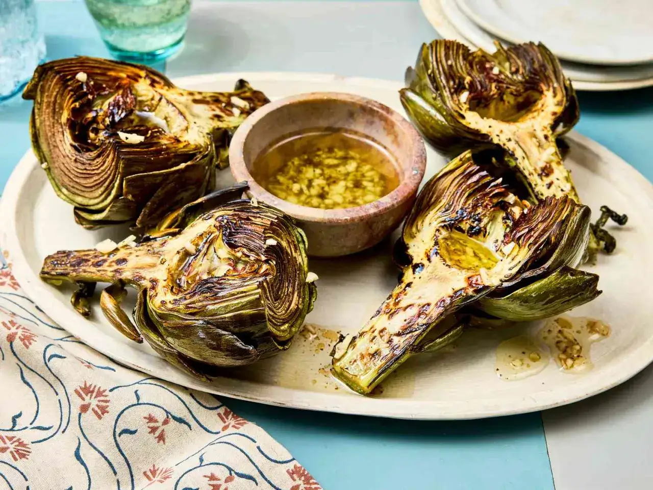 Delicious grilled artichoke halves, brushed with olive oil and garlic, served with a dipping sauce. A perfect grilled artichoke recipe.
