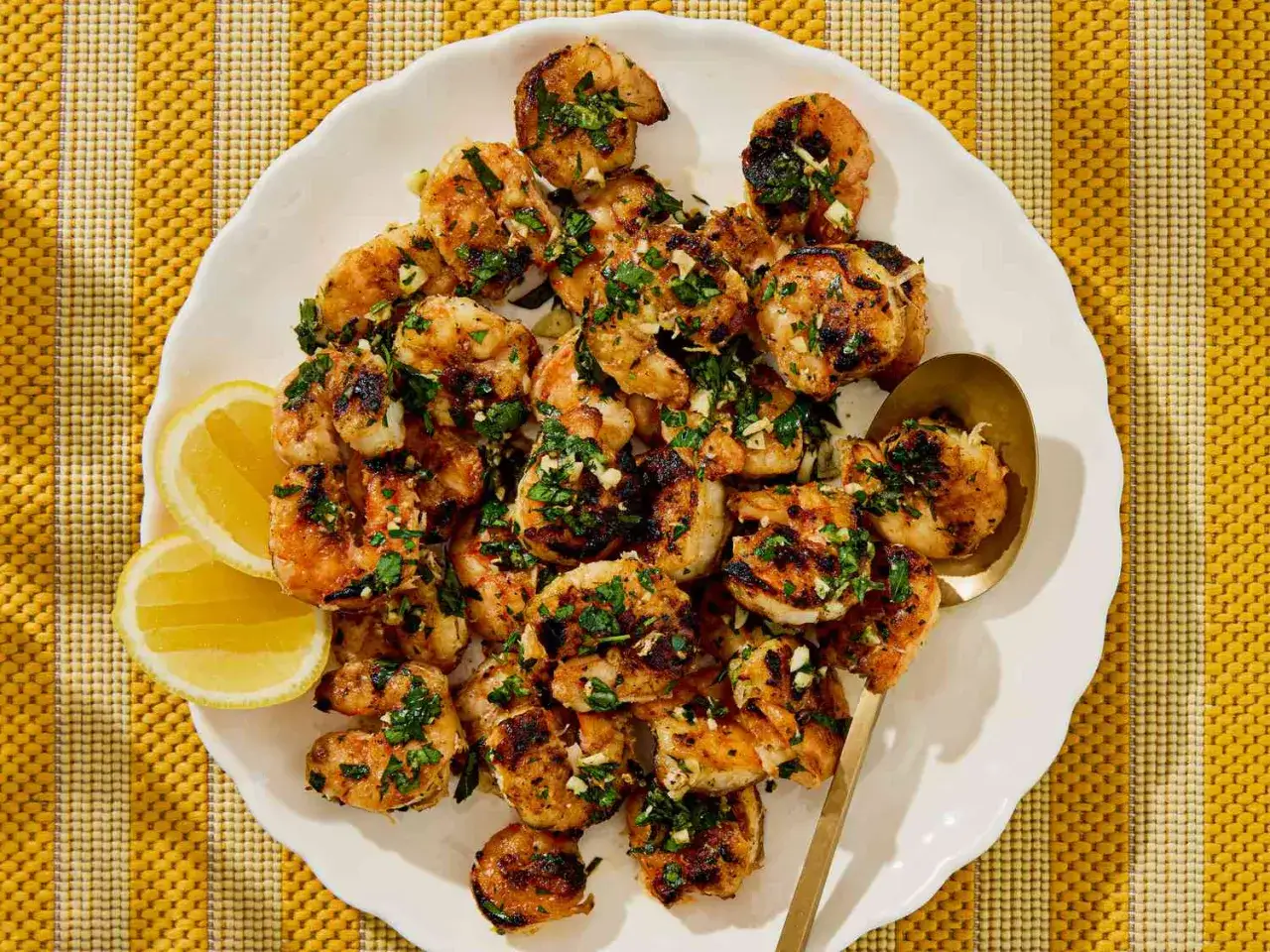 Garlic herb grilled shrimp, a delicious addition to any of your shrimp recipes, served with lemon wedges on a white plate.