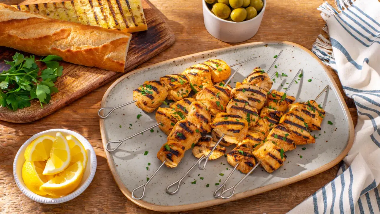 Juicy chicken tapa skewers, grilled to perfection, served with lemon wedges, olives, and toasted baguette slices.