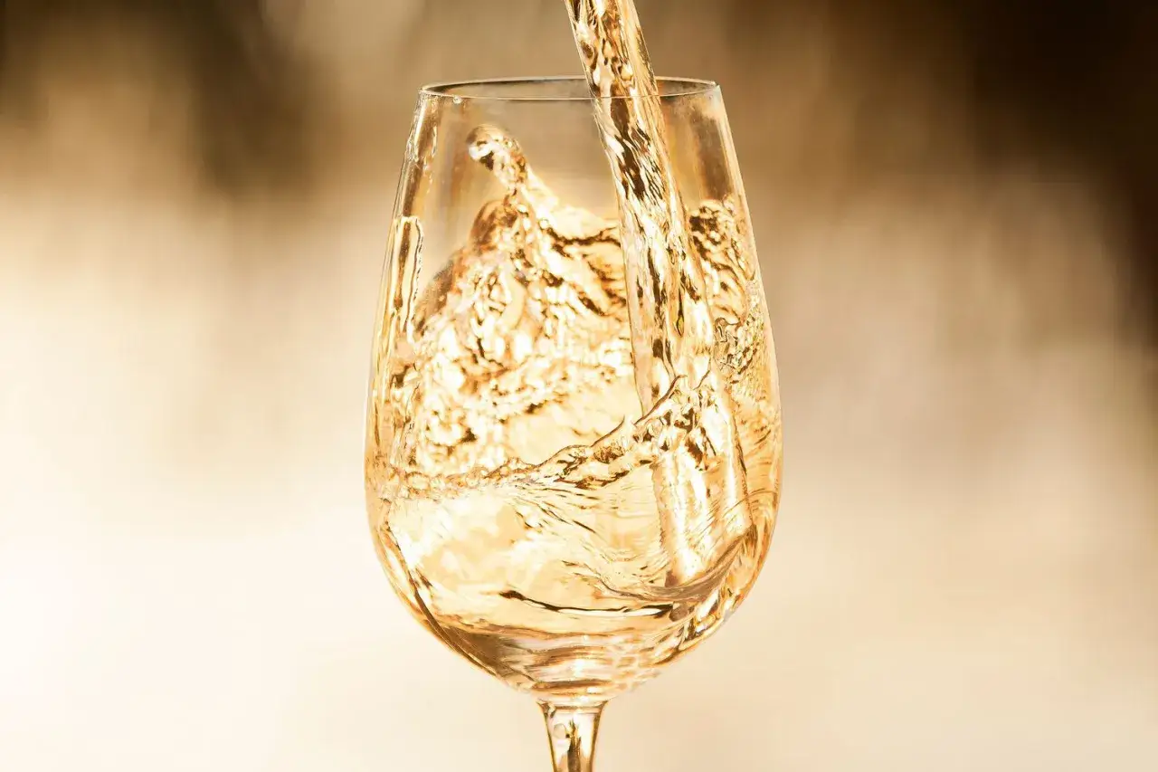 Golden Marsanne wine is poured into a glass, creating a beautiful cascade of liquid.