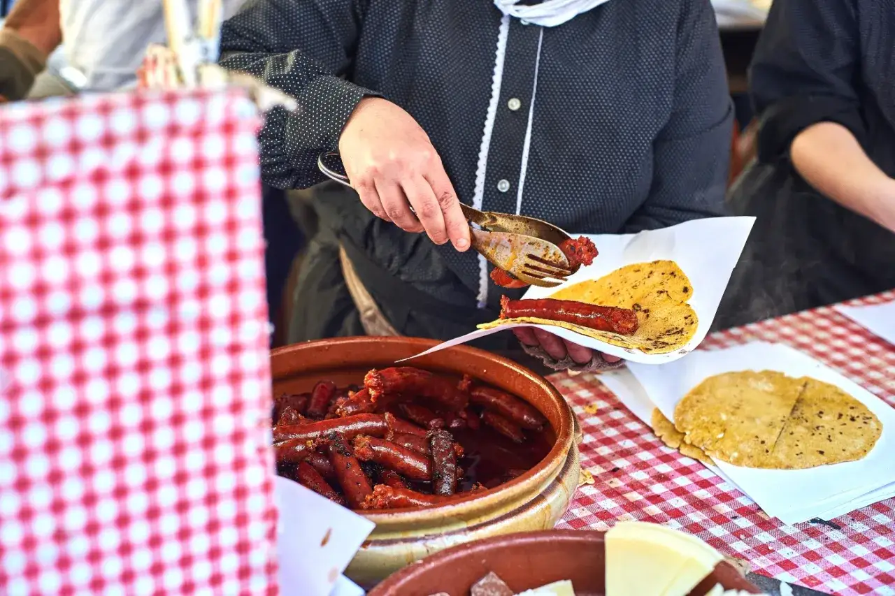 A person serves a chistorra sausage onto a tortilla, part of a delicious chistorra recipe.