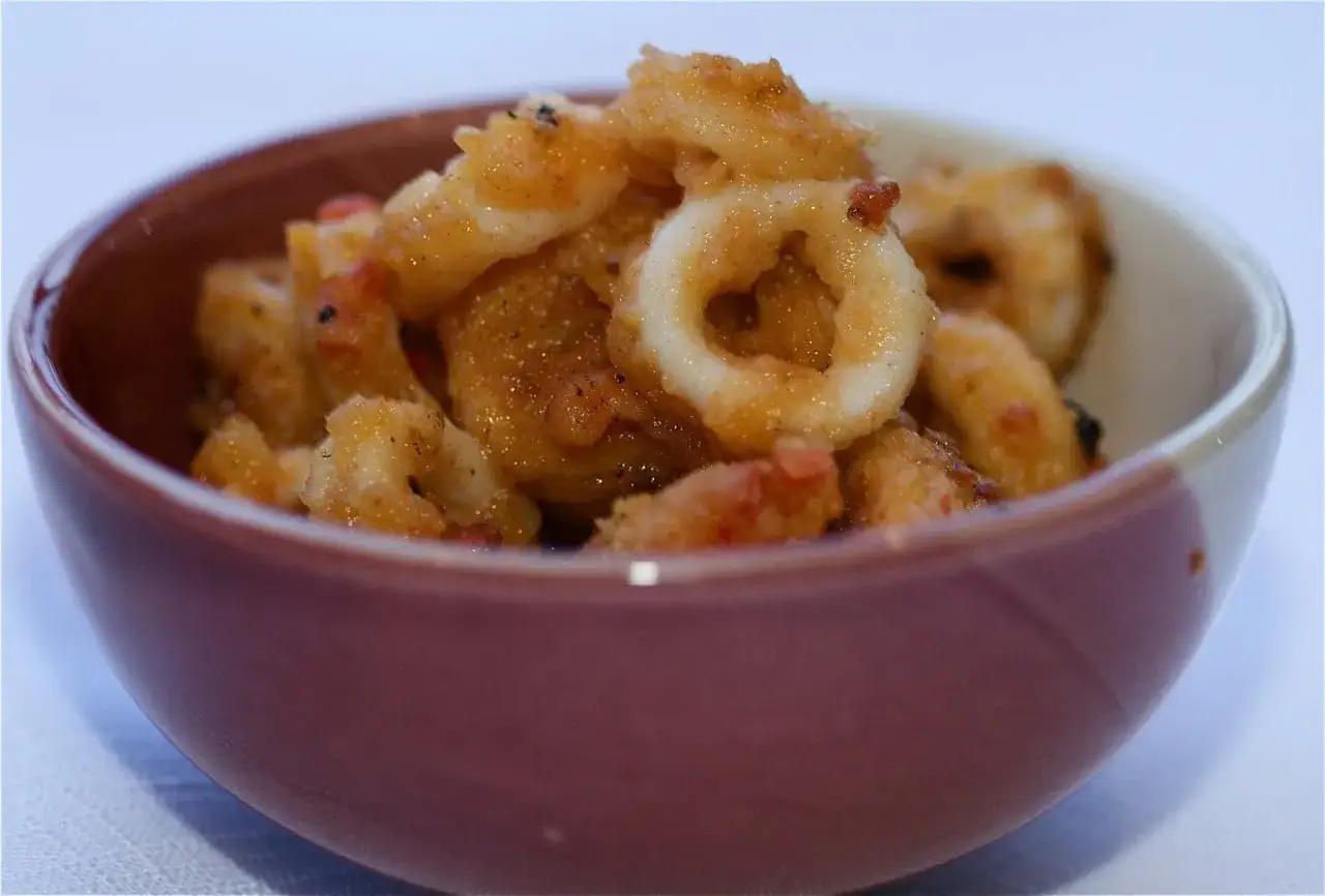 A bowl of crispy rabas fritas, golden brown and seasoned, ready to be enjoyed.