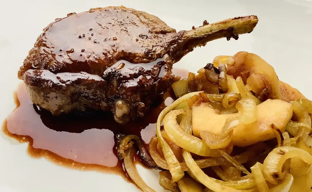 A succulent Iberico pork chop recipe, glazed with a rich sauce and served with caramelized onions and apples.
