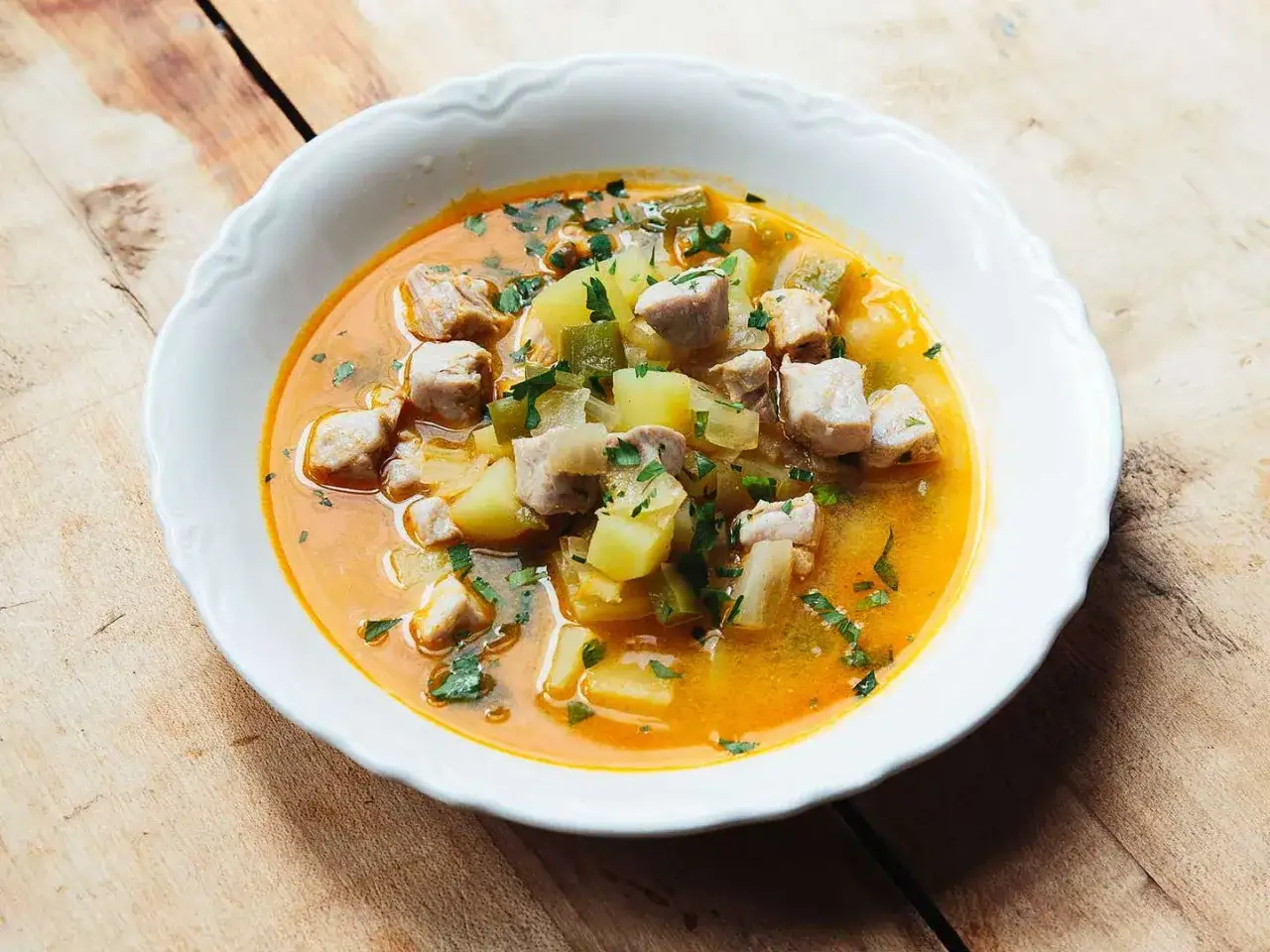 A hearty bowl of marmitako recipe, featuring tender tuna chunks, potatoes, and leeks in a rich, savory broth, garnished with fresh parsley.