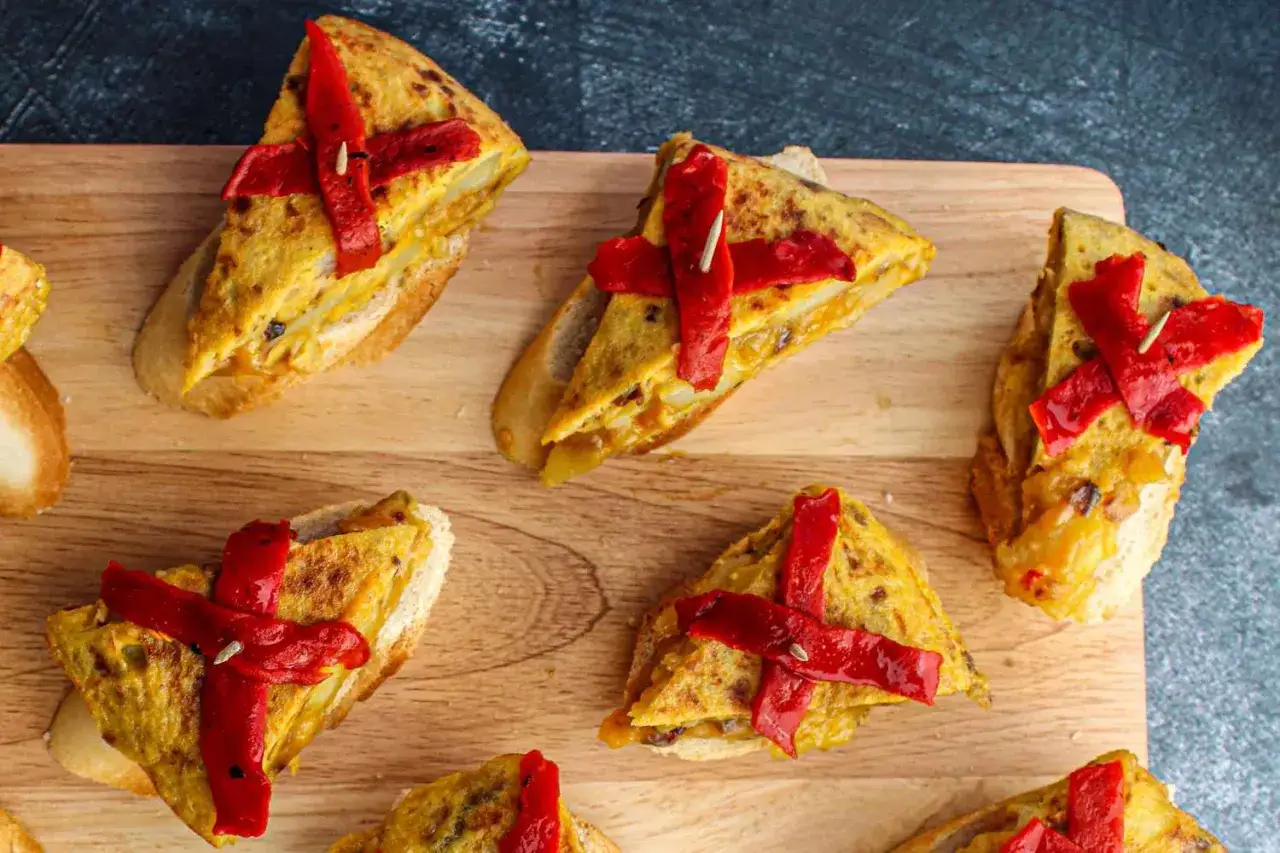 Delicious pincho recipes featuring tortilla espa&ntilde;ola on toasted bread, topped with vibrant red peppers. Perfect for tapas!