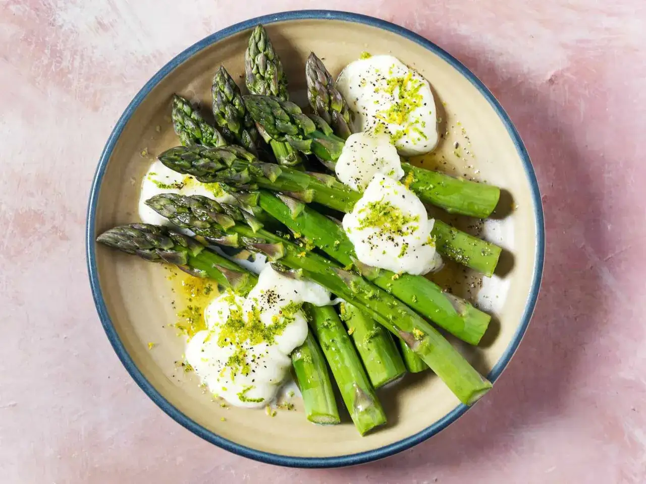A simple way to make asparagus: steamed spears topped with dollops of creamy cheese, lemon zest, and black pepper.