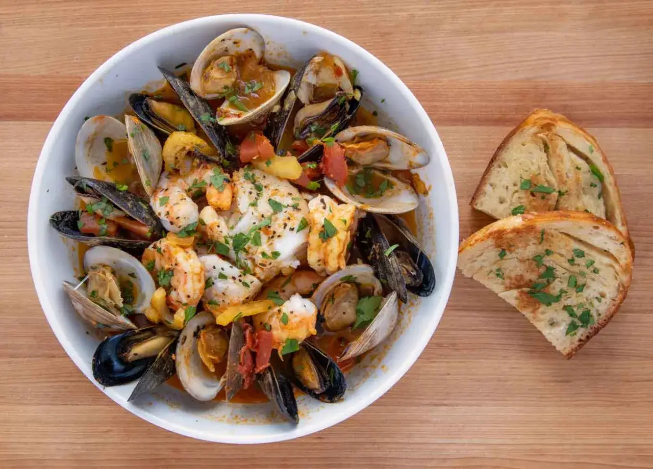 A delicious seafood stew, reminiscent of Spanish fish recipes, brimming with clams, mussels, shrimp, and flaky white fish, served with crusty bread.