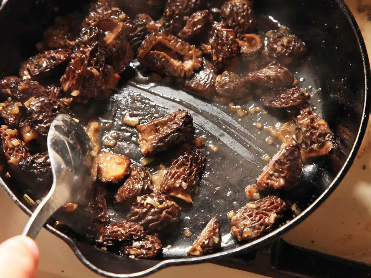 Sautéing morel mushrooms in a cast-iron skillet with shallots. This is the best way to cook morel mushrooms, bringing out their earthy flavor.