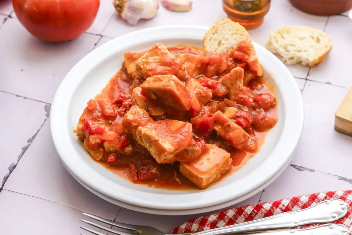 A hearty dish of atun en salsa de tomate, with chunks of tuna in a rich tomato sauce, served with crusty bread.