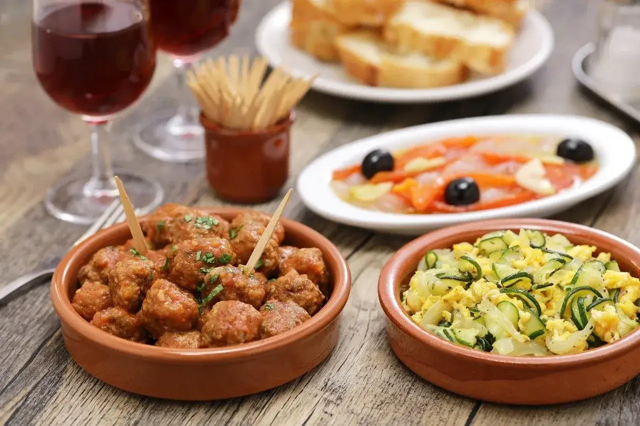 A delicious spread of albondigas in Spain, served with other tapas and red wine.