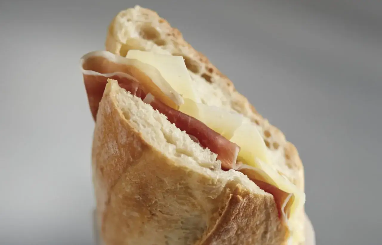 A delicious bocadillo with crusty bread, thinly sliced prosciutto, and creamy cheese.