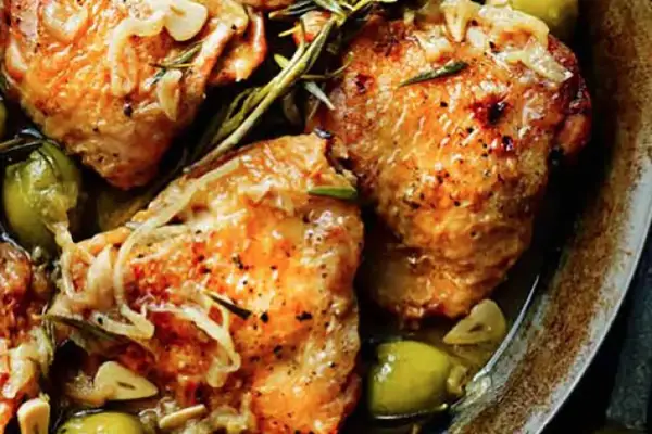 Juicy chicken tapa with olives, garlic, and rosemary, seasoned with pepper and herbs, served in a rustic dish.