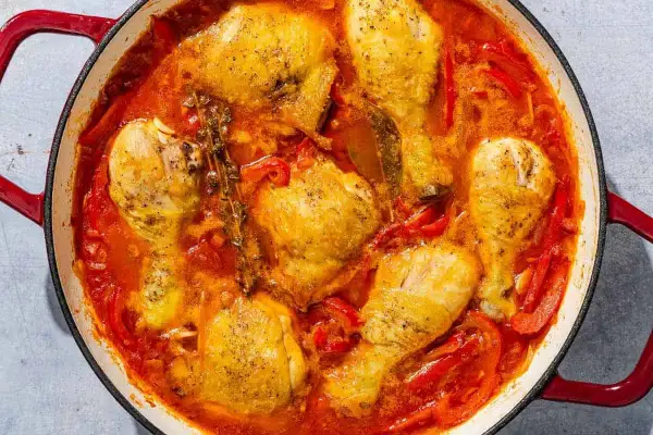A hearty chicken basquaise simmers in a rich tomato and pepper sauce, with sprigs of thyme adding an aromatic touch.