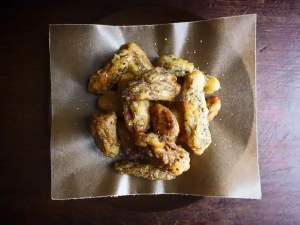 Crispy, golden fried morel mushrooms, lightly salted, piled on brown parchment paper. A delicious appetizer.