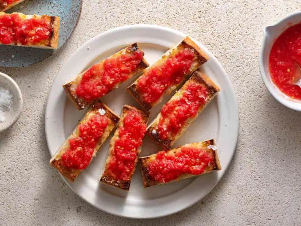 A plate of pan con tomate, toasted bread slices topped with fresh, grated tomatoes and sea salt.