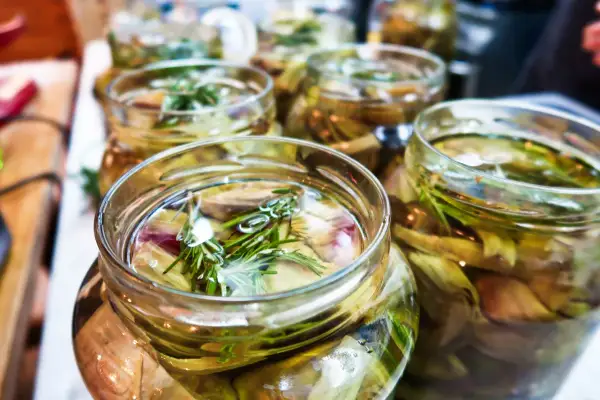 Jars filled with pickled artichoke hearts and rosemary sprigs, ready for a delicious meal.