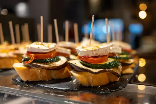 A delicious charcuterie board featuring stacked tapas on toasted bread, topped with goat cheese, tomato, zucchini, and eggplant.