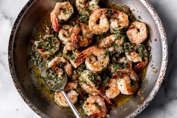 A close-up of a pan filled with succulent shrimp, glistening in a flavorful herb and garlic sauce. These are perfect for quick and delicious shrimp recipes.