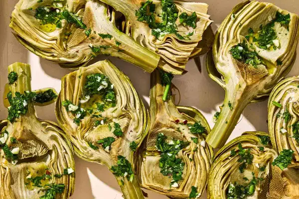 Halved artichokes, seasoned with herbs and garlic, ready for a delicious grilled artichoke recipe.