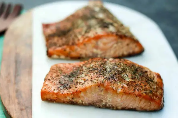 Two seasoned salmon fillets, ready to be smoked. Learn how to smoke salmon in an electric smoker for a delicious meal.